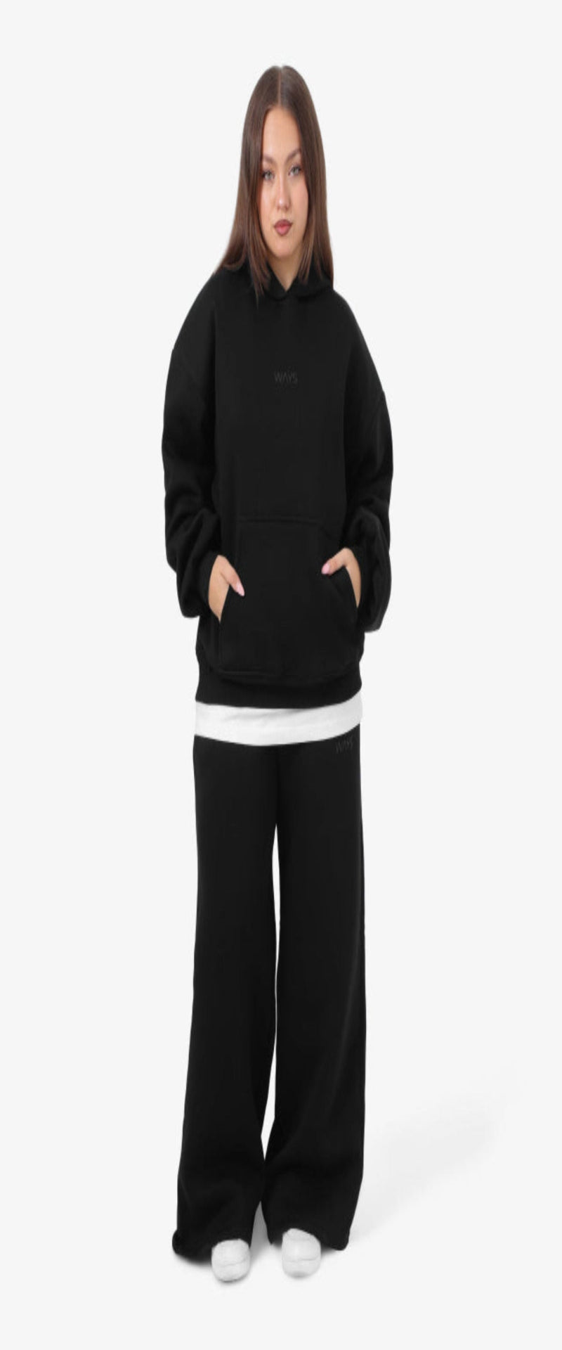 Person wearing a black hoodie and black pants on a white background